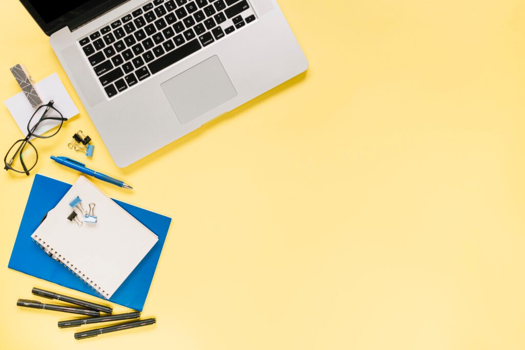 open laptop with office stationeries yellow background